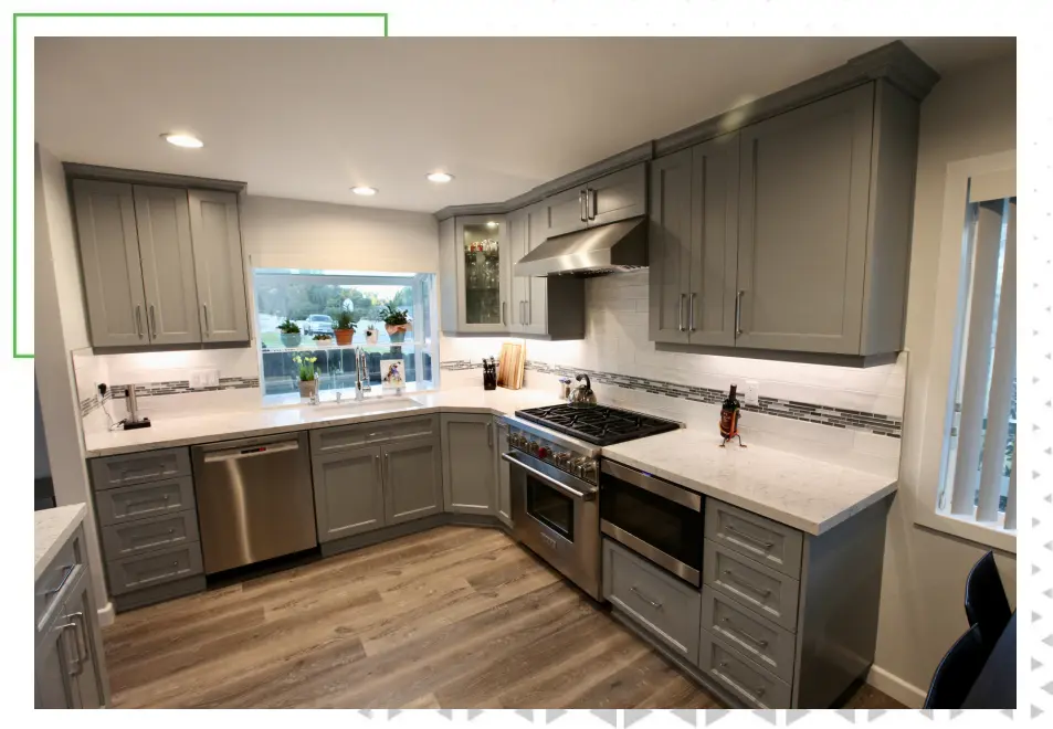 A kitchen with grey cabinets and white counter tops.